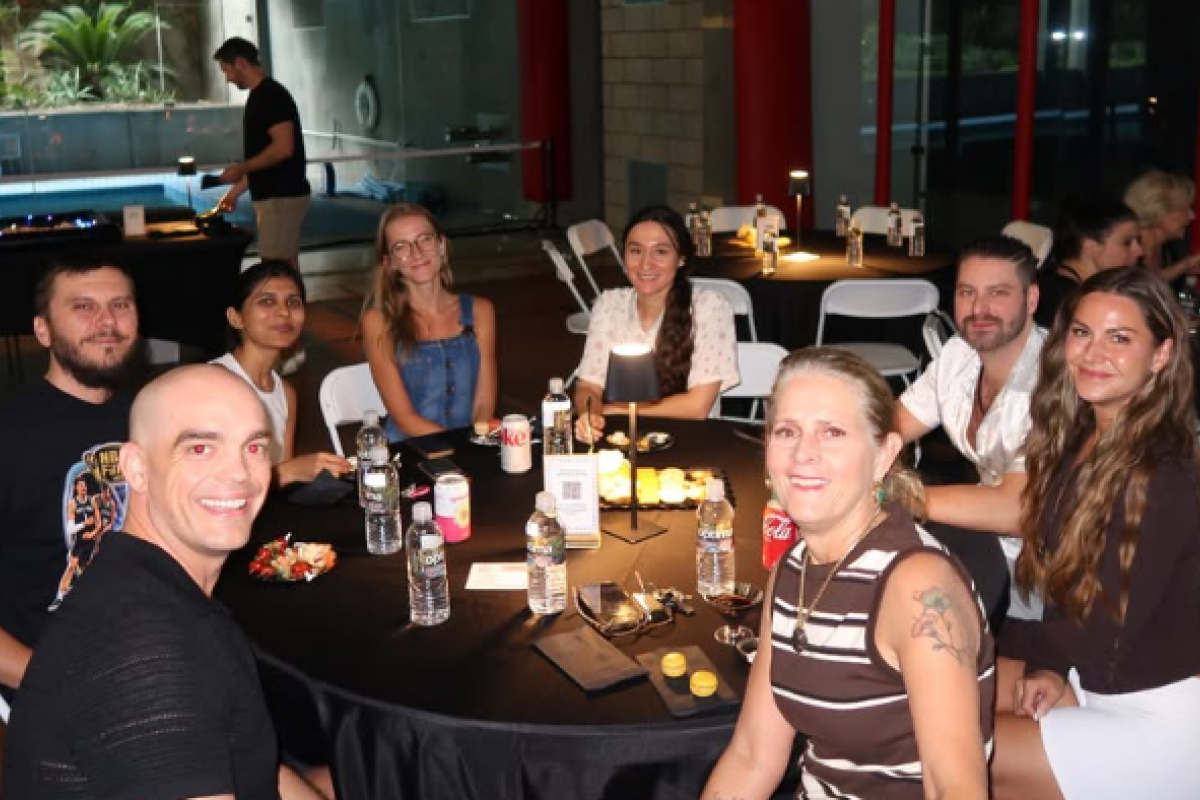 A group of people sitting around a round table at an evening event.