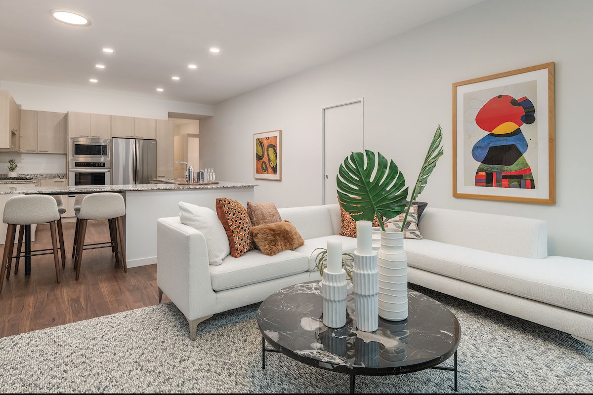 Modern living room with white sofa, abstract art, marble table, and open kitchen—perfect for a modern home.