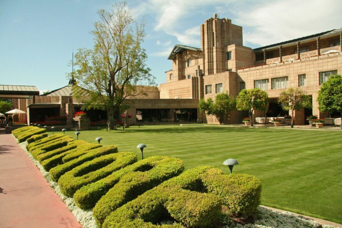 A manicured lawn with “ARIZONA BILTMORE” in bushes fronts Arizona’s grand art-deco architecture masterpiece.