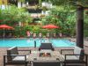Modern poolside patio with red umbrellas, lounge chairs, and fire pit—perfect for Sky Deck evenings amid lush greenery in the background.