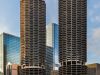 Two round, twin skyscrapers with scalloped balconies in downtown Chicago, surrounded by modern buildings.