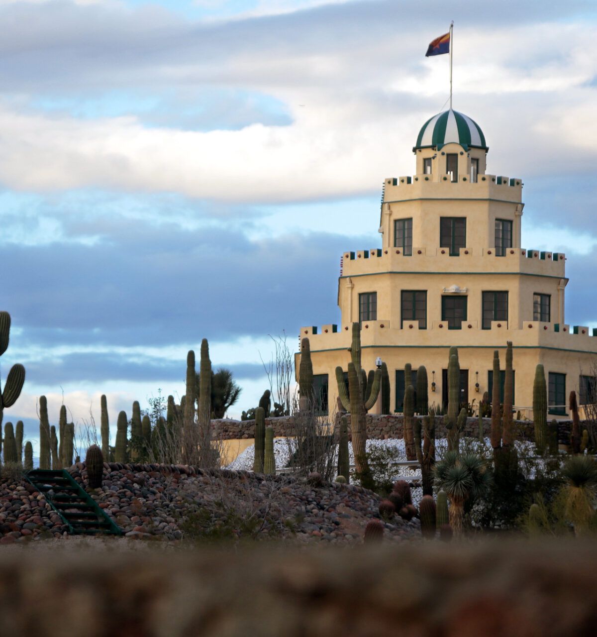 A tiered, white architectural treasure with a dome, surrounded by cacti under a cloudy Scottsdale sky.