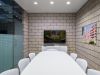 Modern conference room with Optima designs, a white table, chairs, TV, and building photos—ideal for meetings or remote work.