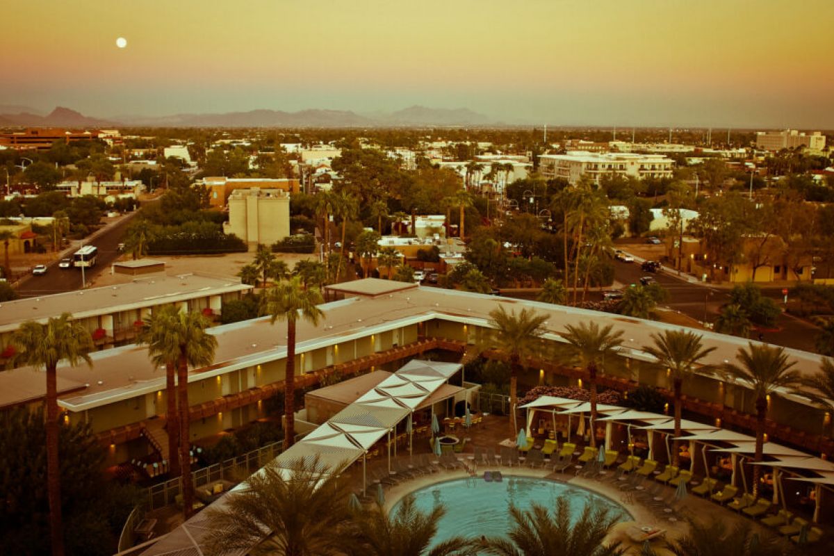 Aerial view of Hotel Valley Ho and pool at sunset, showcasing Scottsdale architecture with city and mountain backdrops.
