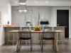 Modern kitchen and dining area with wooden cabinets, set table, and two black chairs—perfect for Hosting at Home.