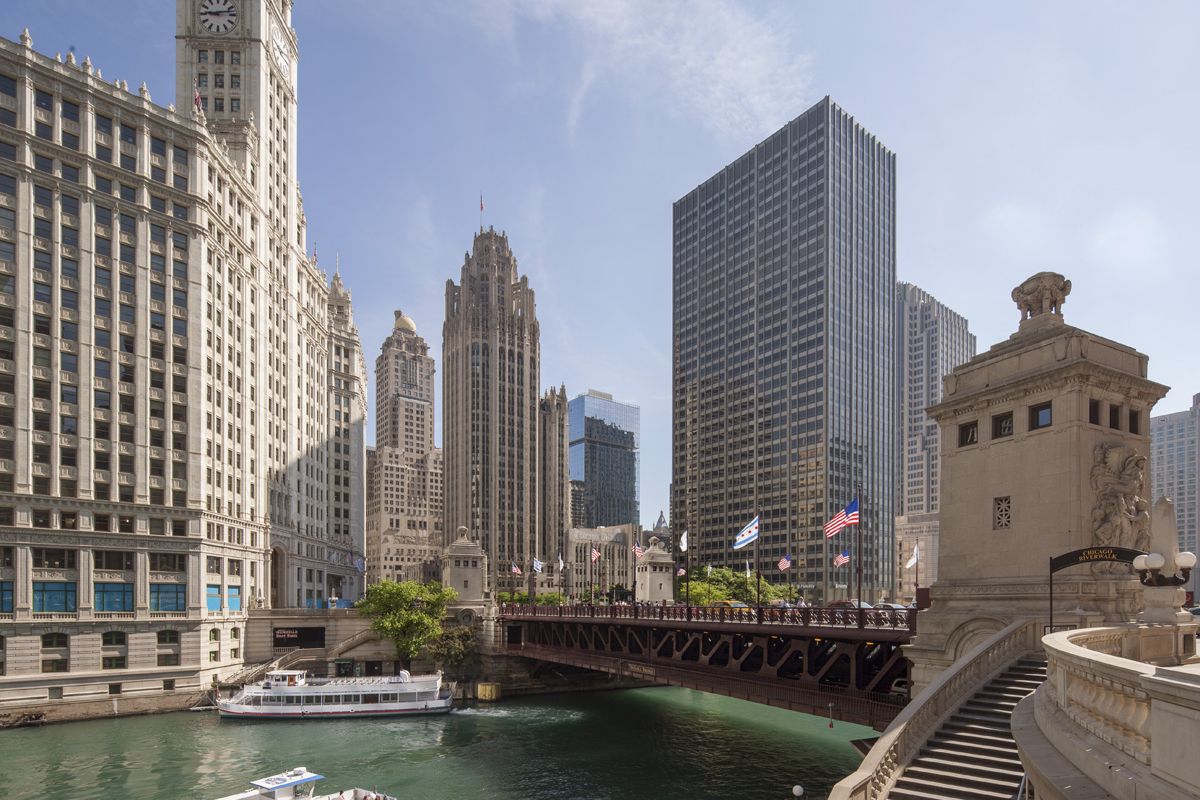 A tour boat glides through the Chicago River, blue space and downtown skyscrapers inspiring mental wellness under a clear sky.