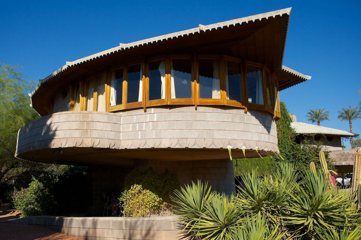 Modern house with rounded stone walls and desert plants, echoing Phoenix architecture like the David and Gladys Wright House.