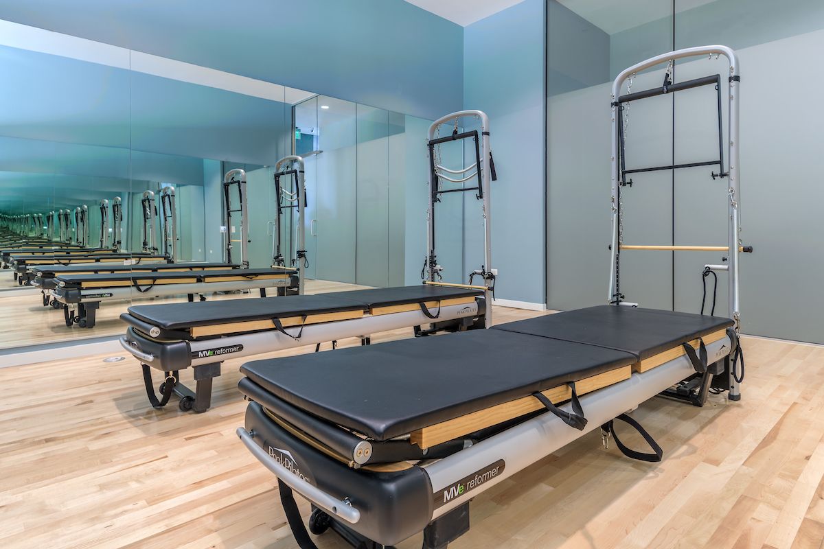 A Pilates studio with two reformer machines on a light wood floor, inviting you to discover the health benefits of a stronger self.