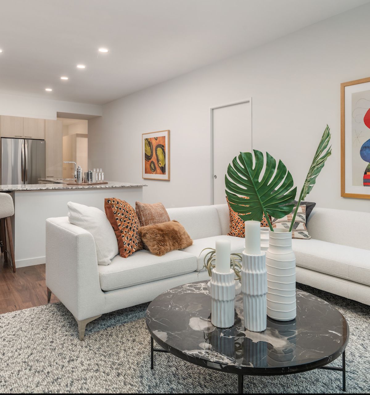 Modern living room with white sofa, abstract art, marble table, and open kitchen—perfect for a modern home.