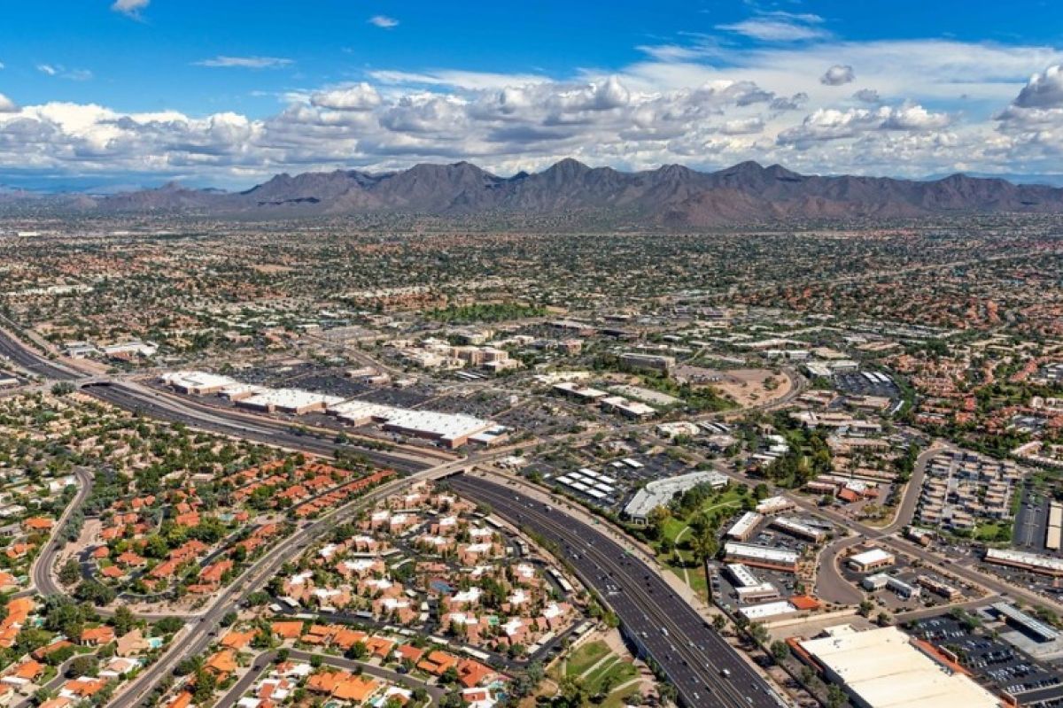 Aerial view of a city with highways, buildings, and mountains—perfect for anyone moving from California to Arizona.