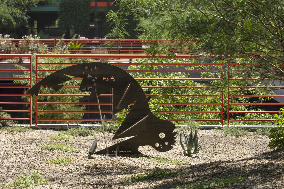 Metal fish art sculpture stands among wood chips and plants, echoing the creative spirit of Optima's lobbies and their unique furniture.
