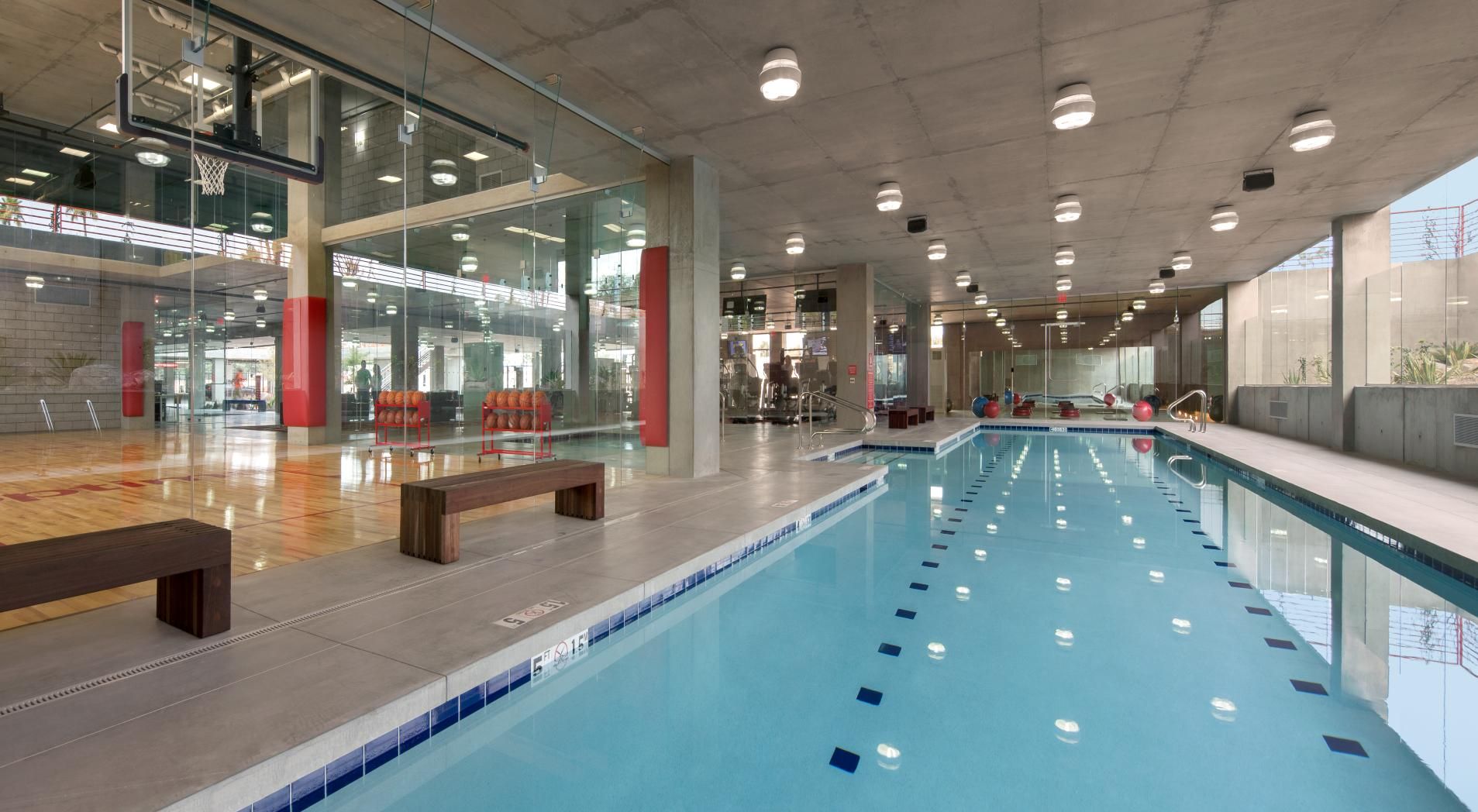 Indoor sports complex with a swimming pool, basketball court, and fitness area at Optima Sonoran Village apartments.