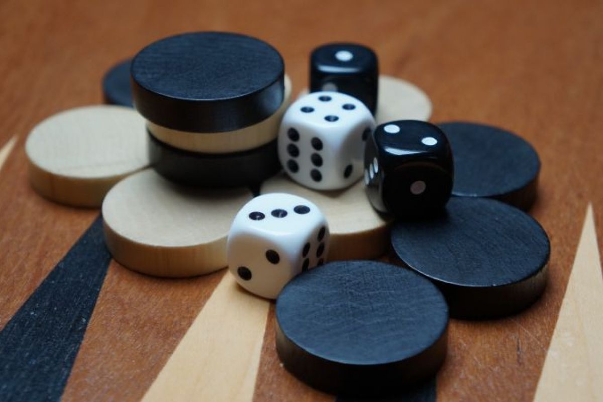 Black and white dice and game pieces are stacked on a wooden backgammon board at Optima Sonoran Village.