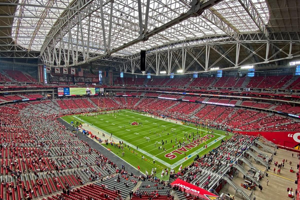 Large indoor stadium in Phoenix, filled with red seats and fans, hosts a live football game reminiscent of Super Bowl LVII.