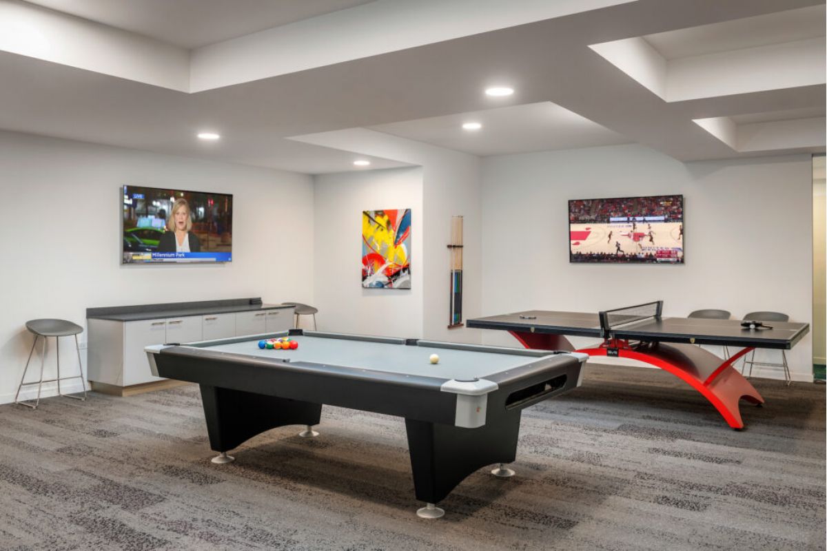 A trending game room with a pool table, Ping-Pong table, two TVs, and colorful wall art.