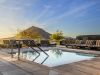 Relax at the small outdoor pool of Optima Sonoran Village, with striped lounge chairs and a stunning mountain sunset backdrop.