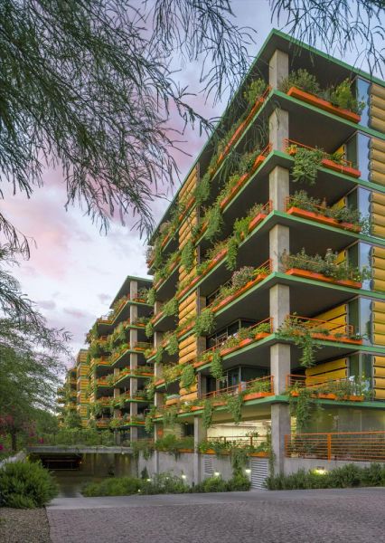 Optima Sonoran Village modern apartment buildings with lush green balconies and yellow accents, surrounded by trees under a colorful sky.