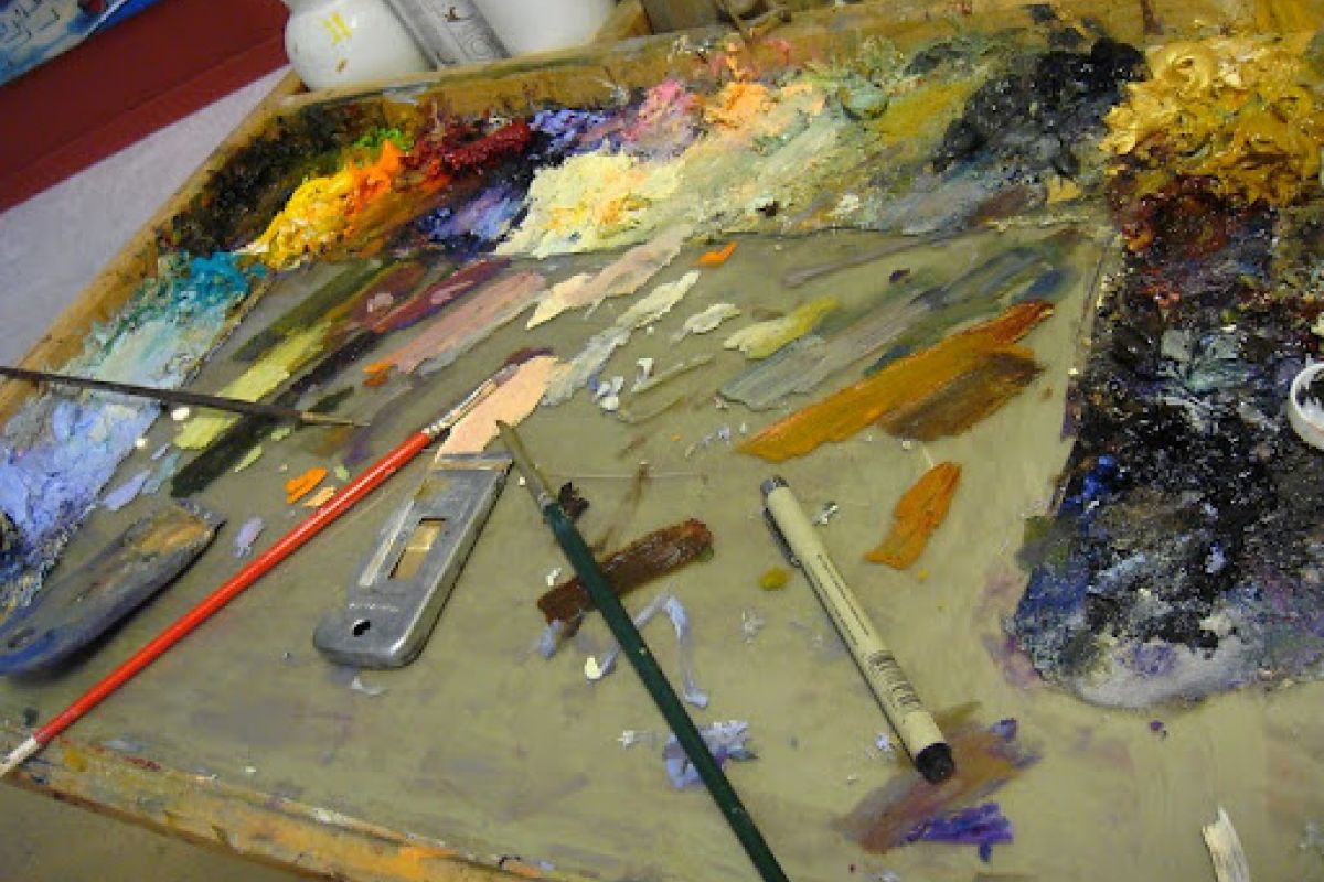 A painter’s palette with mixed colors, brushes, and tools evokes the spirit of a Celebration of Fine Art in Scottsdale.