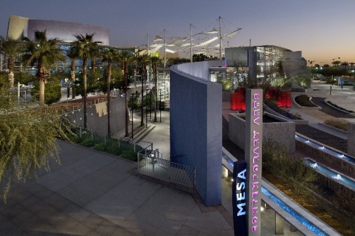 Elevated view of Mesa Arts Center at dusk, featuring palm trees, modern architecture, colorful lights, and lively Fall events.