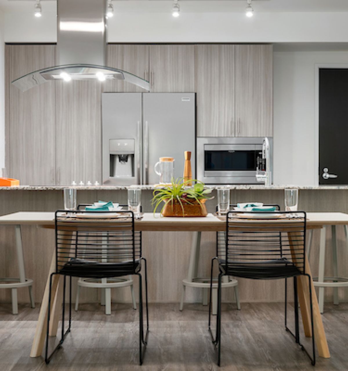 Modern kitchen and dining area with wooden cabinets, set table, and two black chairs—perfect for Hosting at Home.