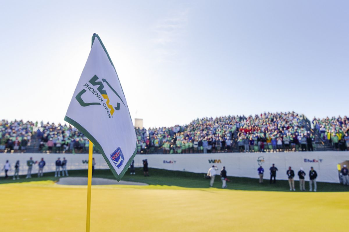A WM Phoenix Open golf flag on the green in Scottsdale with a large crowd of spectators during the 2025 tournament.
