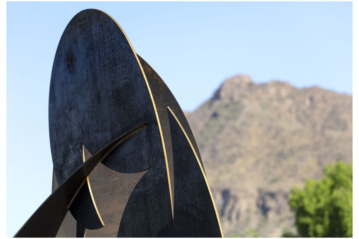 Abstract metal sculpture art set against a mountain and clear blue sky, inspiring creativity in the community.