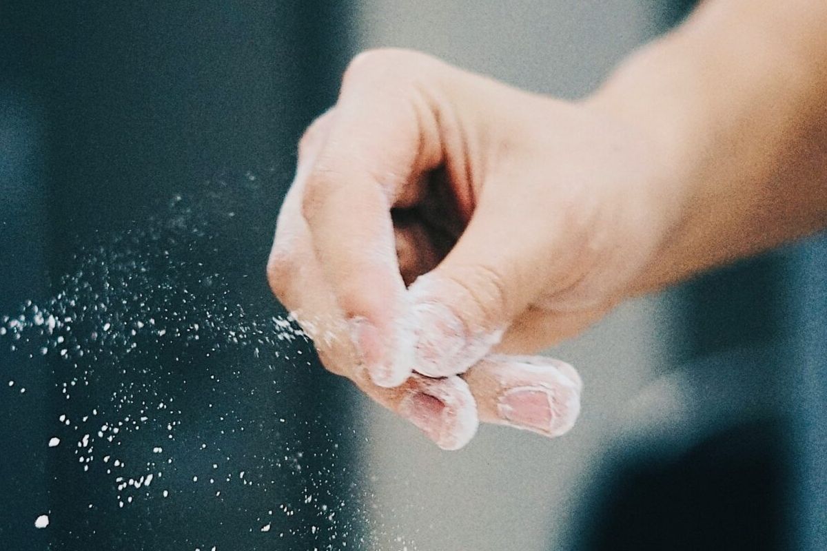 A hand sprinkles flour, white powder dusting the fingers—a simple joy enhanced by Optima induction technology for sustainable living.