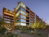 Modern glass and steel building with red accents, a home environment designed to enhance sleep quality, surrounded by desert landscaping at sunset.