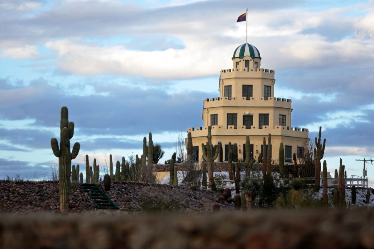 A tiered, white architectural treasure with a dome, surrounded by cacti under a cloudy Scottsdale sky.