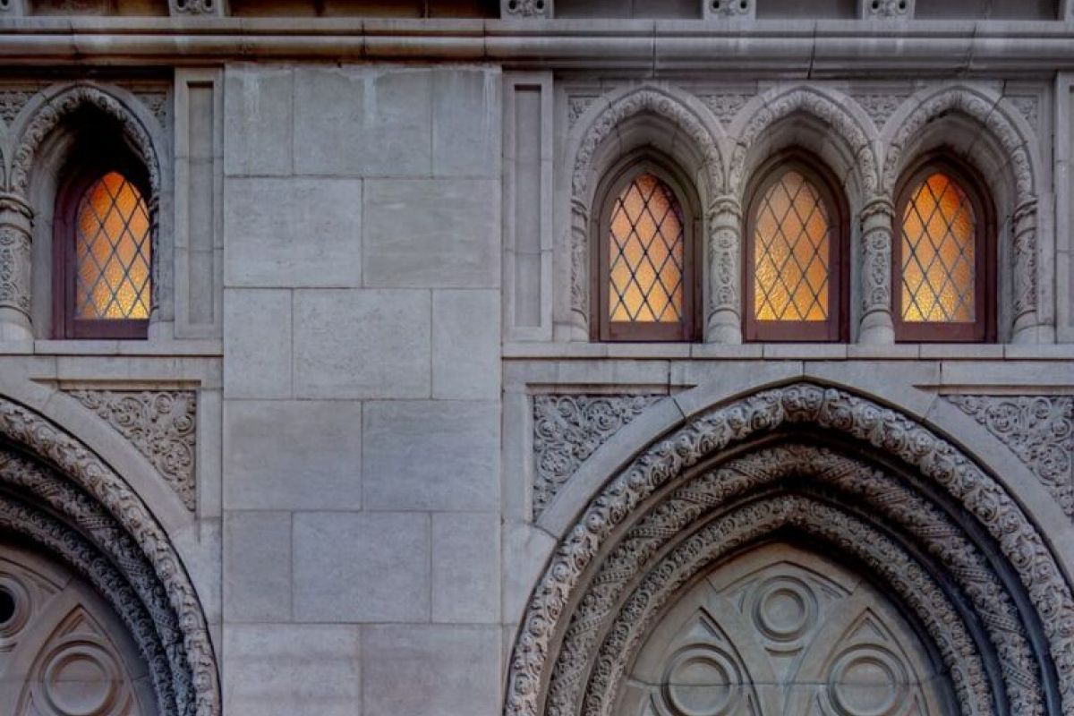 A man with a backpack enters Phoenix’s Monroe Street Abbey, a hidden gem with grand stone arches and ornate windows at dusk.