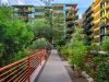 Pathway with red railings leads to modern apartments, offering urban living and walkability amid lush greenery and stylish plant decor.