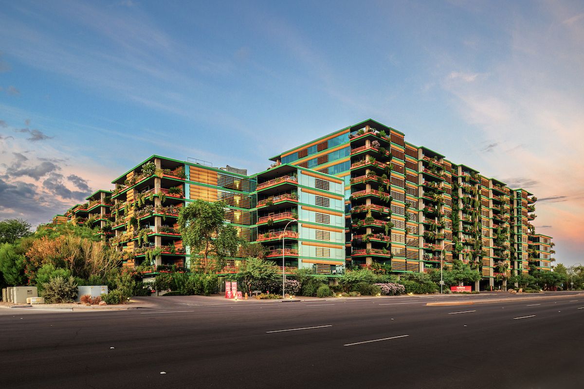 Modern multi-story apartment buildings, common features of Optima Portfolio living, with balconies and greenery at sunset.