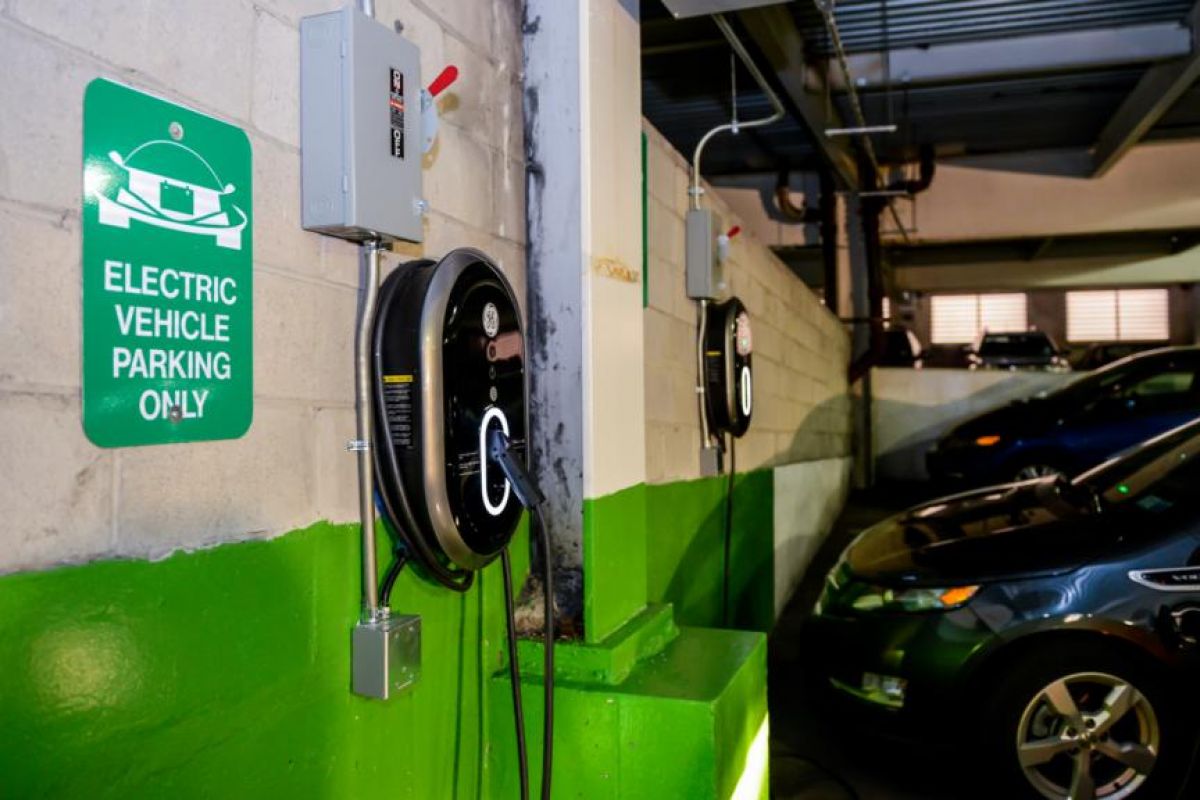 Electric vehicle charging stations in a parking garage, with EVs parked and charging nearby.