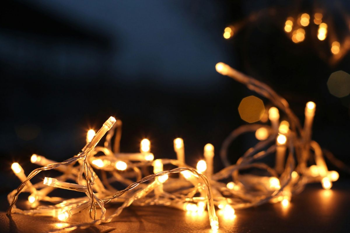 Warm white string lights softly glowing against a dark backdrop, perfect for modernist interiors or cozy holiday decorating.