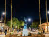 Nighttime street scene with a bronze statue in a roundabout, glowing palm trees, and Scottsdale ArtWalk ambiance.