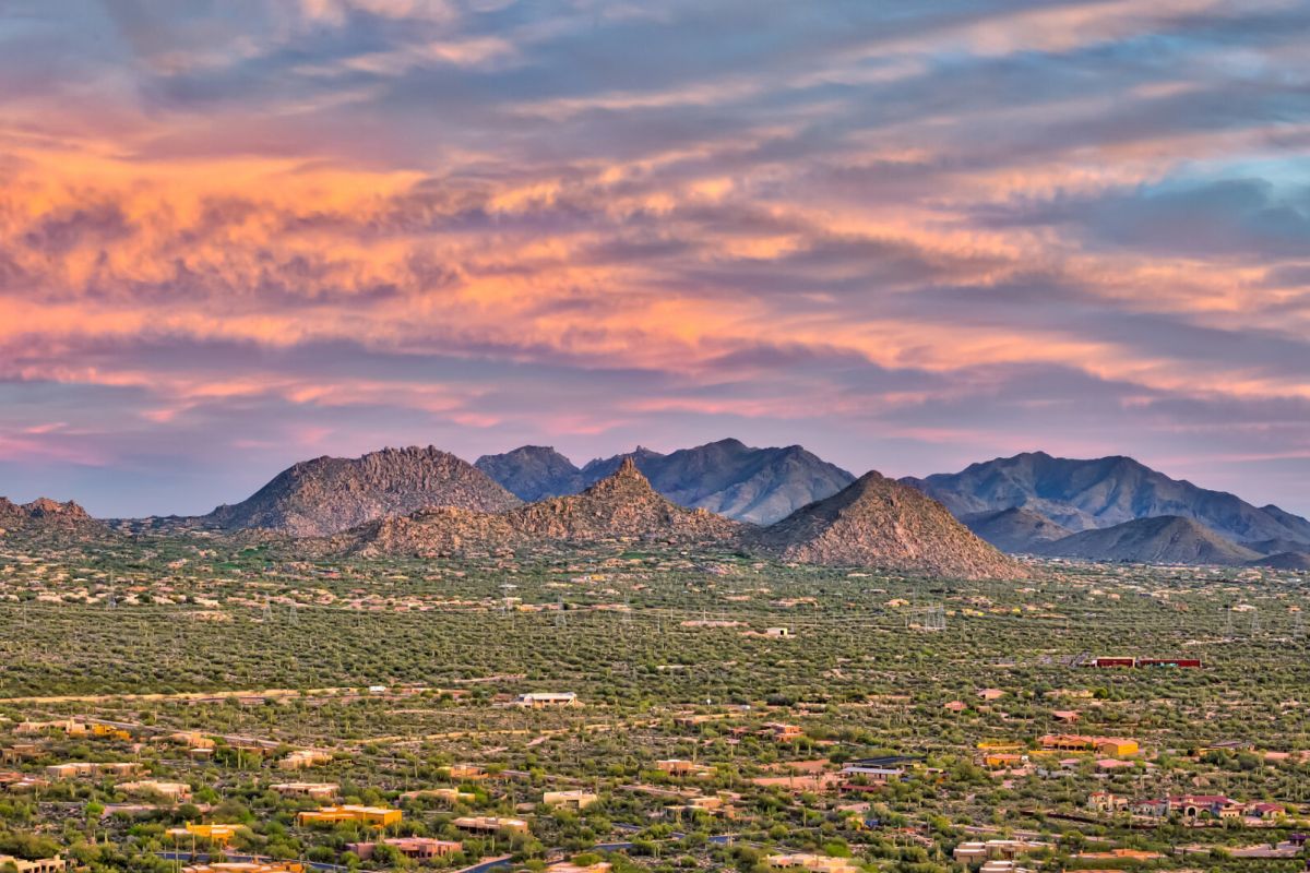 Colorful sunset sky over McDowell Sonoran Preserve, with scattered houses and distant mountains—perfect for exploring Scottsdale’s desert beauty.