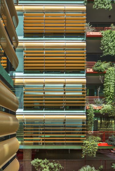 Optima Sonoran Village modern apartment building with yellow blinds and green plants on balconies, showcasing vertical and horizontal lines.