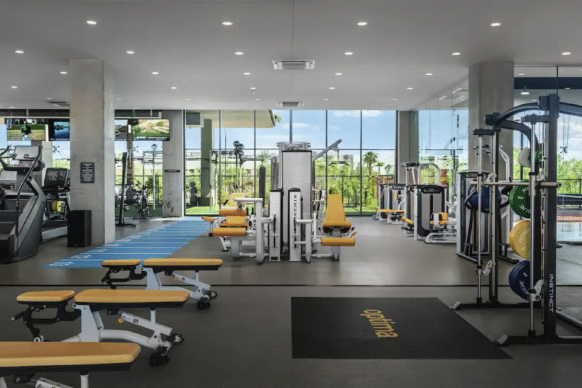 Optima modern gym with yellow and white benches, exercise machines, and large windows—perfect for your Winter Wellness routine.