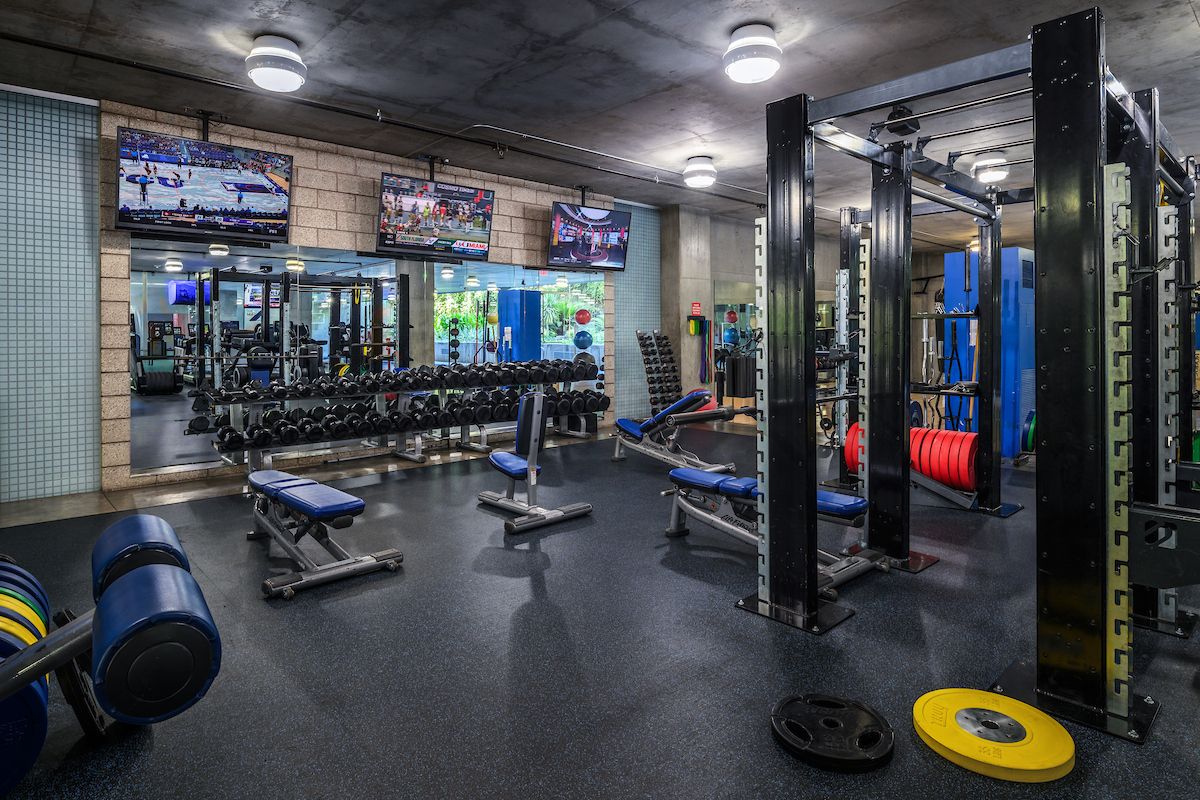 Modern fitness center with weight machines, benches, dumbbells, mirrors, and TVs—perfect for your daily habit.