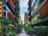 A walkway at Optima Sonoran Village with orange sunshades, lush biophilic design, and greenery on balconies and ground level.