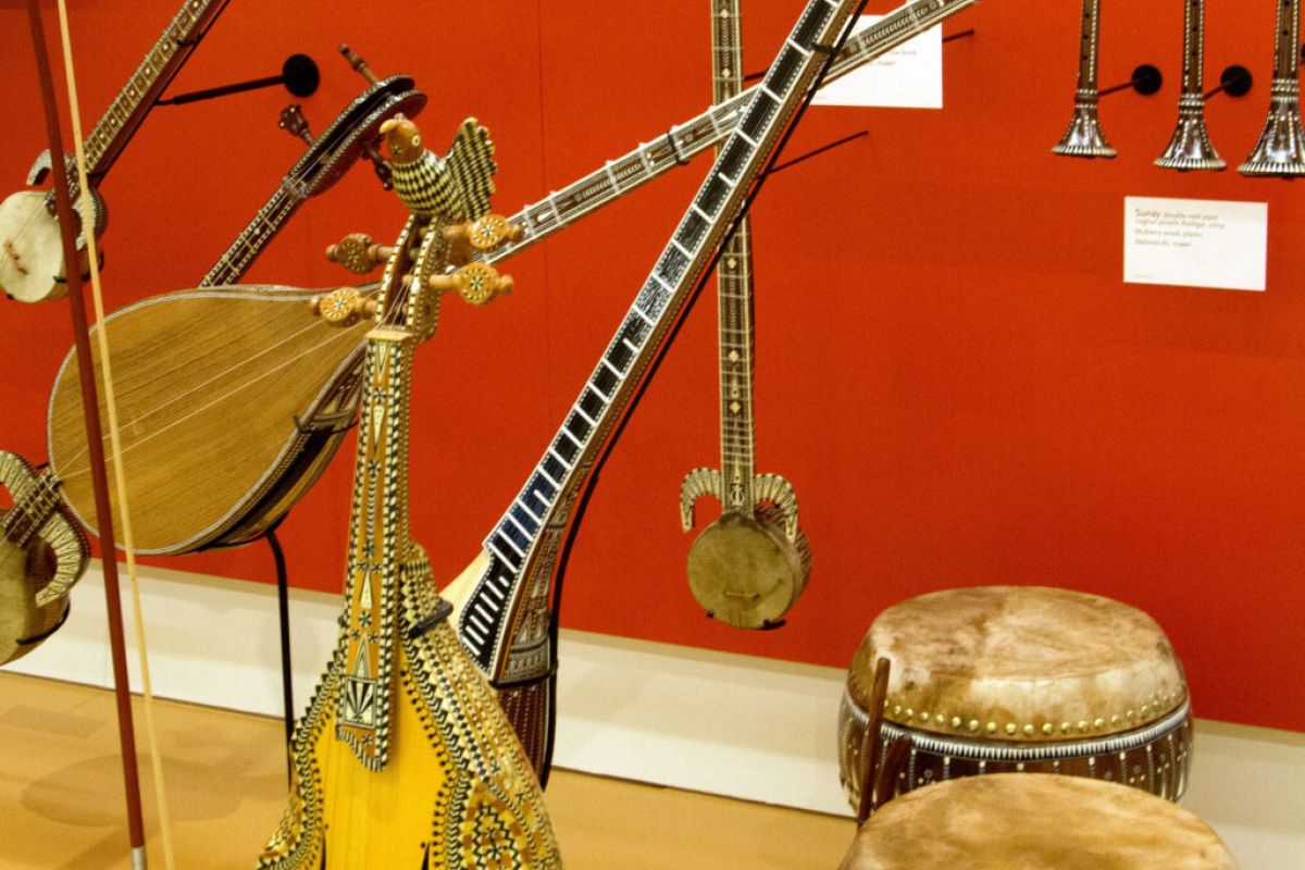Traditional string instruments, drums, and trumpets displayed against a red wall at the Musical Instrument Museum in Scottsdale.