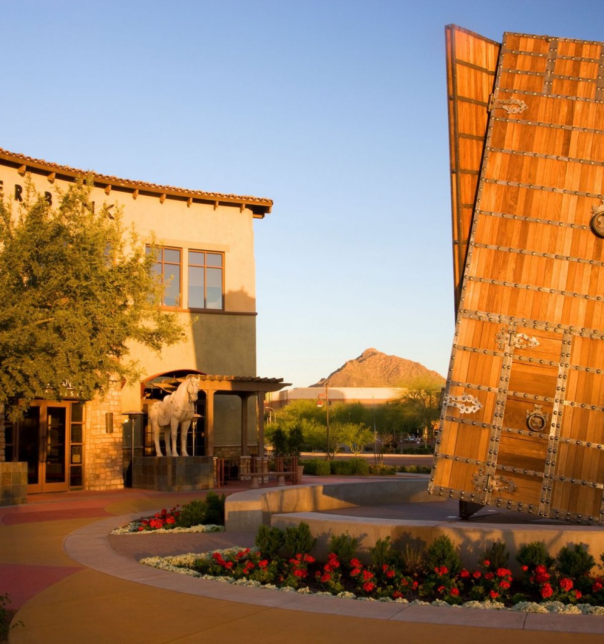 Large metallic door sculpture stands upright in a plaza, with buildings and mountain in the background at Fashion Square Downtown Scottsdale Arizona.