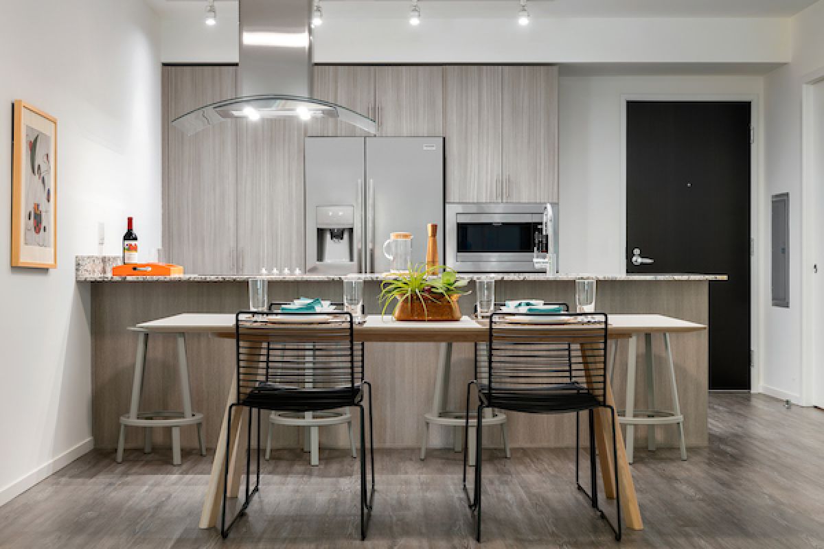 Modern kitchen and dining area with wooden cabinets, set table, and two black chairs—perfect for Hosting at Home.