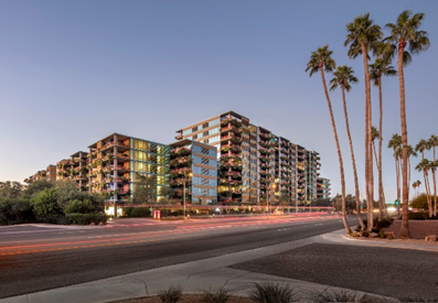 Experience the Optima lifestyle in modern apartments with balconies, palm trees, and blurred traffic at dusk.