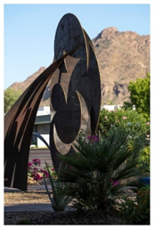Abstract metal sculpture with curved shapes stands in the garden, reflecting the community's appreciation for art and nature.