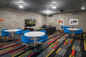 Modern lounge by Optima Designs with blue chairs, round tables, black sofas, and art—perfect for your new home office or Work Now space.