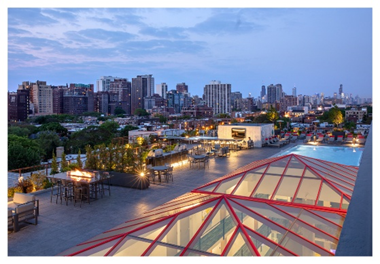 Rooftop amenities at Optima Sky Decks with a pool, seating areas, and stunning city views at dusk under a partly cloudy sky.