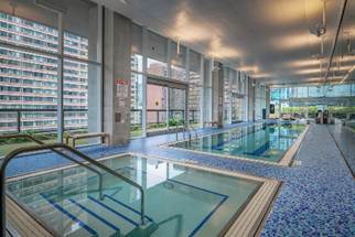 Indoor pool with city views, lounge chairs, and blue mosaic tiles.