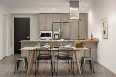 Modern kitchen and dining area with wooden table, metal chairs, and stainless steel appliances.